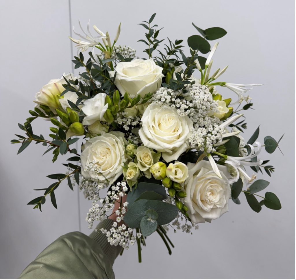 All white and green wedding bouquet with gypsophilia, playa blanca roses, eucalyptus, white freesia, nerine lilies and spray roses.
